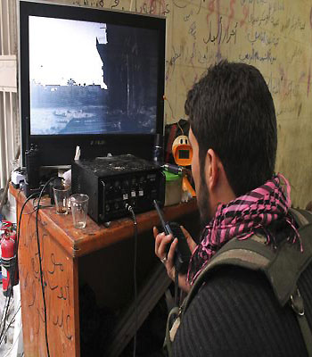A member of the Free Syrian Army looks at a monitor showing surveillance footage of a street, in the old city of Aleppo. (R)