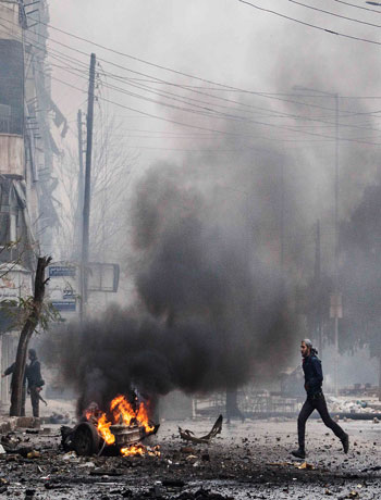 In this Dec. 17, 2012 file photo, a man runs between debris after a mortar shell hit a street killing several people in the Bustan Al-Qasr district of Aleppo, Syria. (AP)