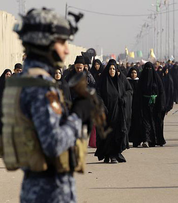 An Iraqi federal policeman stands guard as Shiite pilgrims march to Karbala for Arbaeen in Baghdad, Iraq, Sunday, Dec. 30, 2012.. (AP)