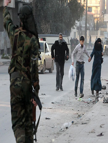 Residents run to take cover as a Free Syrian Army fighter gestures in Aleppo's Bustan al-Qasr district December 30, 2012. (Reuters)
