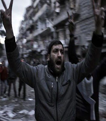 Syrians rush to the location of a building targeted by a missile in the al-Mashhad neighbourhood in the city of Aleppo. (AFP)