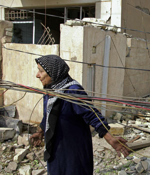 Iraqi woman looks at her destroyed residence at the site where two suicide bombers detonated explosives-laden cars near Al Hamra hotel that houses foreign journalists and an interior ministry complex at Al Jadriyah district, Baghdad, (AFP