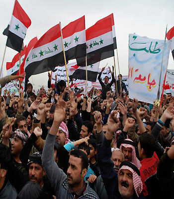 Protesters chant slogans against Iraq's Shiite-led government as they wave representations of Saddam Hussein-era national flags during a demonstration in Ramadi. (AP)
