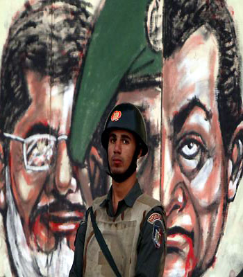 A member of Egypt's Republican Guard stands in front of a wall of the presidential palace bearing caricatures of President Mohamed Mursi and former president Hosni Mubarak in Cairo. (R)