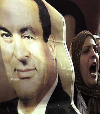 A supporter of ousted former Egyptian President Mohammed Hosni Mubarak stands near a poster of him at a protest outside a High Court in Cairo. (R)