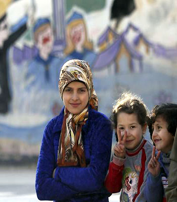 Internally displaced Syrian children gesture as they pose for a photo at a school in Aleppo. (R)