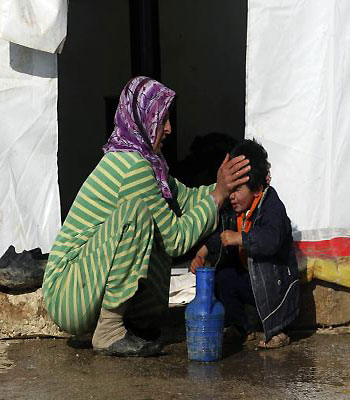 A Syrian refugee cleans a boy's face outside a tent at Bab al-Salam refugee camp in Azaz. (R)
