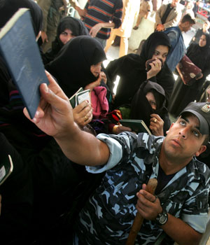 Palestinian policeman helps women to submit passports after Rafah border crossing reopens in Gaza Strip November 26, 2005 (REUTERS)
