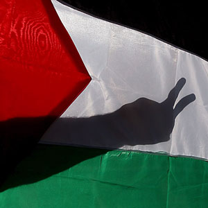 Shadow of member of al-Aqsa Martyrs Brigades is seen on a Palestinian flag after members stormed a government complex in Gaza December 1, 2005 (REUTERS)