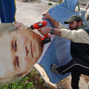 A Lebanese member of the Hezbollah guerilla group puts the final touches on an effigy representing U.S. President George W. Bush, near the Fatma Gate, in Kfar Kila village, on the Lebanese-Israeli border, southern Lebanon, Dec. 2, 2005 (AP)