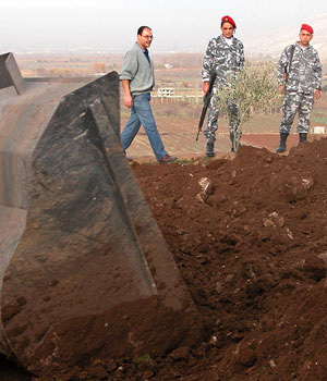 Lebanese policemen watch a bulldozer being used to search for more bodies after a mass grave was found in the eastern town of Anjar, in the Bekaa Valley, Lebanon, December 3, 2005 (AP)