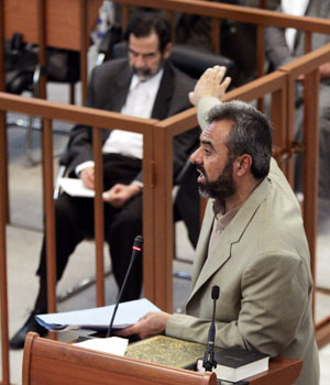 Ahmad Hassan Mohammed Al Dujaili testifies in open court as former Iraqi President Saddam Hussein watches from his seat during his trial in Baghdad's heavily fortified Green Zone December 5, 2005 (REUTERS)
