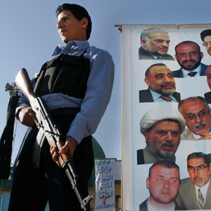 An Iraqi policeman stands guard next to an election campaign poster for the United Iraqi Alliance with pictures of the list's candidates in Baghdad, Iraq, prior to the upcoming December 15 parliamentary elections (AP)