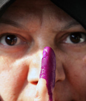 An Iraqi woman holds up her inked finger after voting in the Iraqi parliamentary elections at a polling station in south Tehran December 14, 2005 (REUTERS)