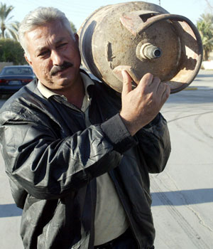 An Iraqi man carries a gas cylinder through the streets of Baghdad, 19 December 2005 (EPA)