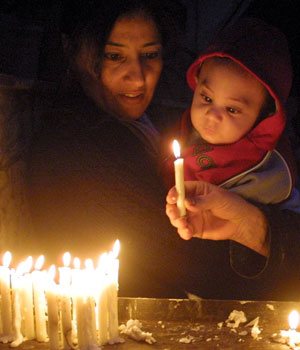 An Iraqi Christian woman lights a candle during a prayer at the Marry church in the Karrada district, central Baghdad, on Saturday, 24 December 2005 as Iraqi Christians celebrate on Christmas Eve (EPA)
