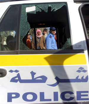 An Iraqi man is seen through a damaged police car window at Al-Tahriyat square in Baghdad, 30 December 2005, after a road side bomb targeted a police convoy (EPA)