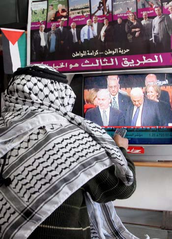 A Palestinian in the West bank city of Hebron watches television news footage of Israeli prime Minister Ariel Sharon (EPA)
