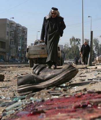 An Iraqi man walks past blood and glass and a shoe following a roadside bomb (AP)