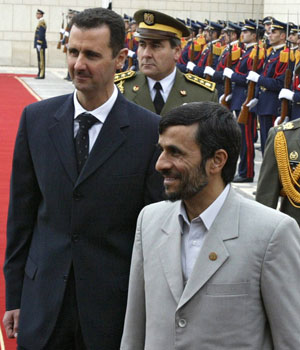 Syrian President Bashar al-Assad (L) and his Iranian counterpart Mahmoud Ahmadinejad (R) review the honour guard at Damascus airport, 19 January 2006 (AFP)