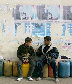 Iraqi boys sit underneath tear off election posters as they wait for their turn to buy petrol in central Baghdad, 20 January 2006 (AFP)