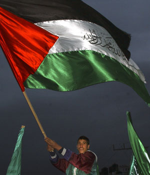 A Palestinian youth, waving the Palestinian flag, celebrates the victory of Hamas in parliamentary elections, in the West Bank City of Jenin, Jan. 26, 2006 (AP)