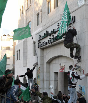 Hamas activists climb on the parliament in the West Bank city of Ramallah January 26, 2006 (REUTERS)