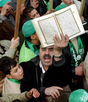 A Palestinian supporter of the Hamas displays the Muslim holy book of the Quran as he celebrates the victory of Hamas in the parliamentary elections in West Bank City of Nablus, Jan. 26, 2006 (AP)