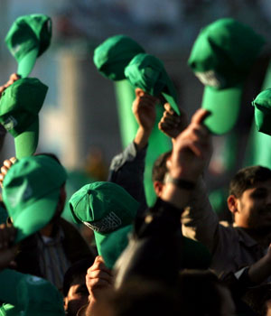 Palestinian Hamas supporters hold up their green hats as they chant slogans during a rally celebrating the group's victory in parliamentary elections, in the Khan Younis Refugee Camp, southern Gaza Strip, Jan. 27, 2006 (AP)