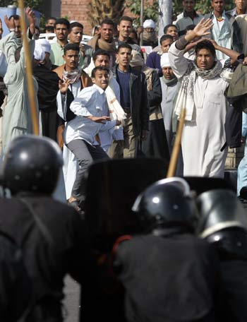 A man, center, throws a rock at police as clashes break out outside the port in Safaga in Egypt (AP)