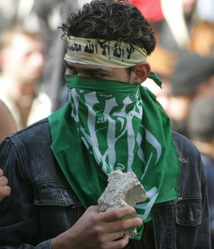 A masked demonstrator holds a rock as demonstrators hurled stones and set fire to the building housing the Danish consulate in Beirut in the latest violent protest against cartoons of the Prophet Mohammed, 5 February 2006 (AFP)