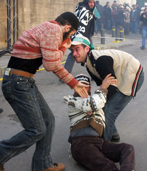 Protesters help a fellow Islamist who fell down as Lebanese riot police fired tear gas to disperse a demonstration, 05 February 2006 in Beirut against the publication of cartoons depicting Prophet Mohammad in European newspapers recently (AFP)