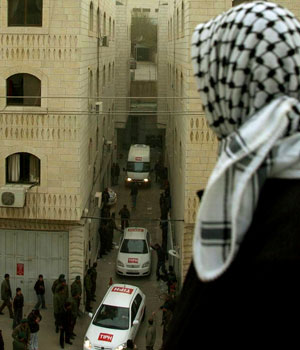 A Palestinian man looks at Temporary International Presence in Hebron, or TIPH, vehicles leave their offices in the West Bank town of Hebron, Feb. 8, 2006 (AP)