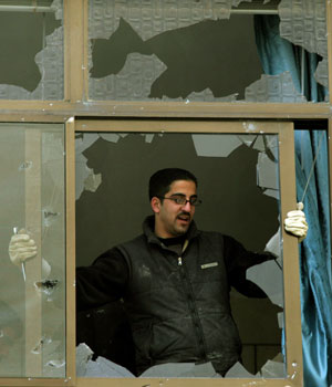 A Palestinian worker removes a shattered window at the Temporary International Presence (TIPH) offices in the West Bank town of Hebron, Feb. 8, 2006 (AP)