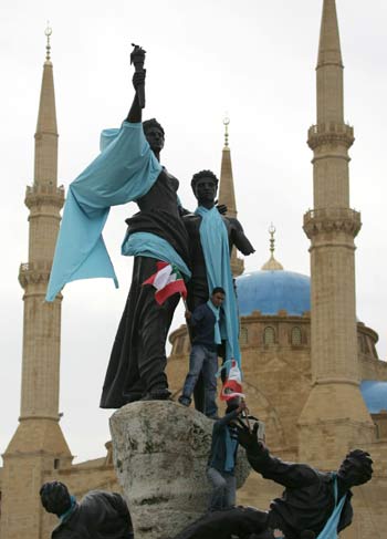 Young Lebanese, holding up national flags, fix blue flags symbolizing the "Truth" (AFP)