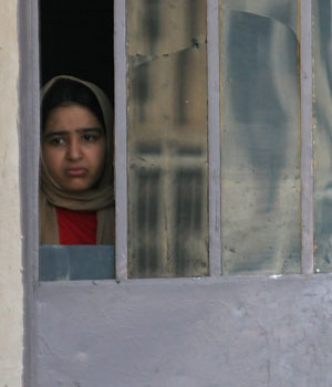 An Iraqi girl watches the scene from behind a door following a car bomb explosion in Baghdad, Thursday, Feb. 16, 2006 (AP)