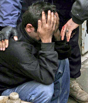 Iraqis calm their relative as he mourns an army captian who was killed by unidentified militants along with a soldier in the northern city of Kirkuk, 16 February 2006 (AFP)