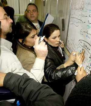 Iraqi stock exchange workers vie to register the value of different stocks at a board in the newly opened Baghdad's bourse, 20 February 2006 (AFP)