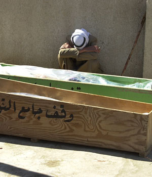 An unidentified relative mourns in the front of the coffins of his family members, in Baquba, 60 kilometers (35 miles) northeast of Baghdad, Iraq, Feb. 25, 2006 (AP)