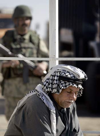 An Iraqi man waits in a gas line as an Iraqi Special Police Commando from the 2nd Battalion 2nd Brigade, also widely known as the "Wolf Brigade" (AFP)