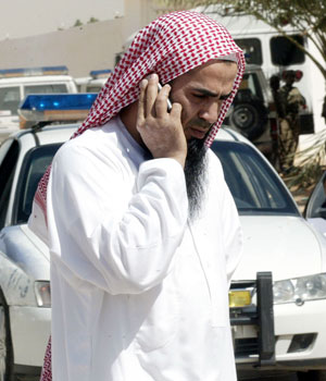 A Saudi man talks on his mobile phone on a road leading to the house where five men were killed during clashes in Riyadh, 27 February 2006 (AFP)