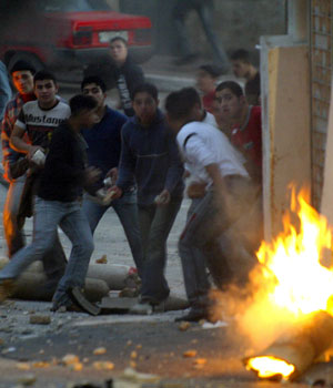 Tires and other debris burn as Palestinian youth throw stones during clash with Israeli soldiers in the northern West Bank city of Nablus 06 March 2006 (AFP)