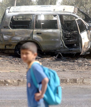 An Iraqi boy passes by a destroyed vehicle of an official convoy following a road side bomb attack in Baghdad, 08 March 2006 (EPA)
