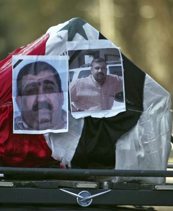 Photographs of senior Iraqi state television editor and driver are pasted on coffin in Baghdad (R)