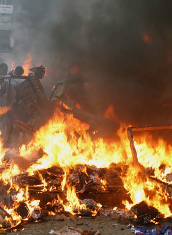 Iraqi residents look at burning debris at market after series of bomb attacks in Baghdad's Sad'r City (R)