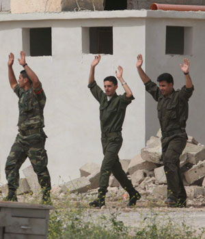 Palestinian security raise their hands over their heads as they leave their headquarters in the West Bank city of Jericho, 14 March 2006 (EPA)