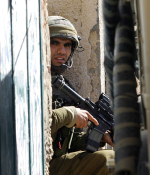 An Israeli soldier takes a position during an army operation in the West Bank town of Jenin,16 March 2006 (AFP)