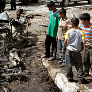 Iraqi children look at wreckage of car following a car bomb explosion, in central Baghdad, Iraq, March 18, 2006 (AP)