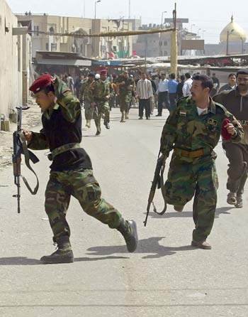 Iraqi police commandos run to the site where a rocket slammed inside a parking lot in the holy city of Karbala, south of Baghdad (AFP)