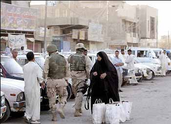 An Iraqi woman watches US soldiers inspect cars in Baghdad (AFP)